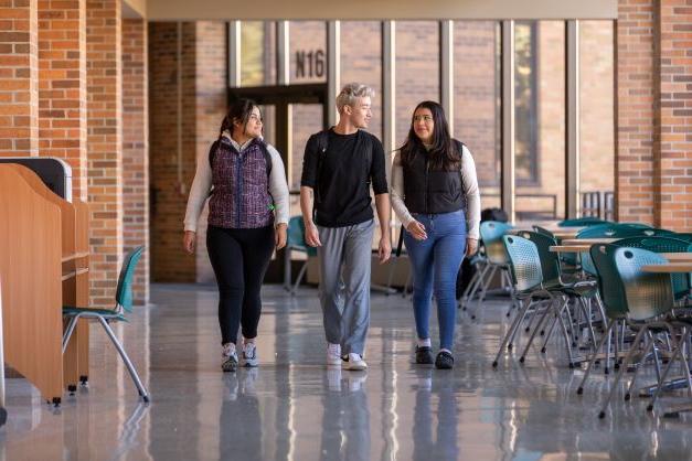 Three students walking in hallway on campus at Anoka Tech